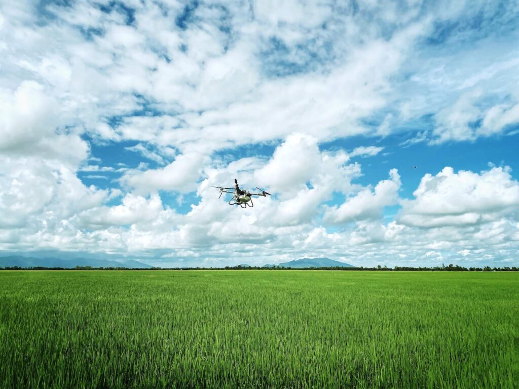 A drone flying over a green field on a cloudy day.